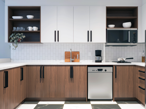 Kitchenette with white cabinets above and imitation brown wood cabinets below, with long black cabinet handles.
